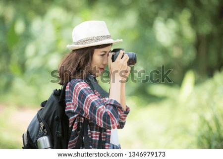 Asian woman hiking with backpack holding camera to traveling in the forest. Hiking enjoying forest landscapes. Relaxation and Holiday Concept.