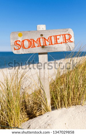 Wooden sign at beach with german word „Sommer“, translating to „summer“