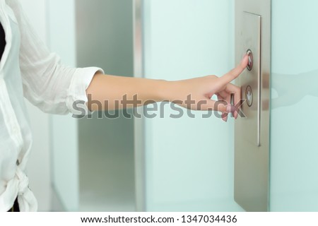 Hand  pressing the elevator button for next levels up 