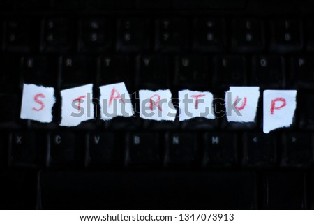 The inscription on scraps of paper on the background of blurred outlines of a computer keyboard. hi-tech startup