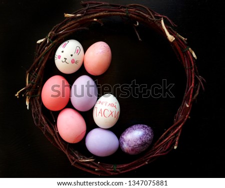 Easter eggs inside branches frame  on black background, Translation on egg text "happy easter"