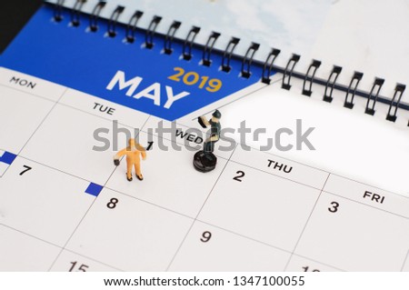 Conceptual photo using miniature workers and calendar background