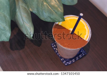 Cocoa with orange beverage on wooden table and leafs in coffee shop.