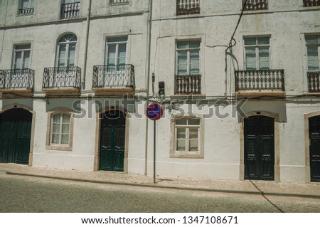 Mansion facade with cracked wall and NO WAITING road sign on sunny day, in front of deserted causeway at Campo Maior. A little town with Roman, Moorish and medieval influences in eastern Portugal.