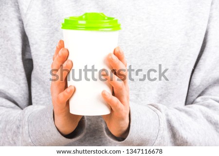 Human hands holding a paper coffee cup with color plastic cap with blank space for design logo and template for blog, social media. Delicious coffee concept