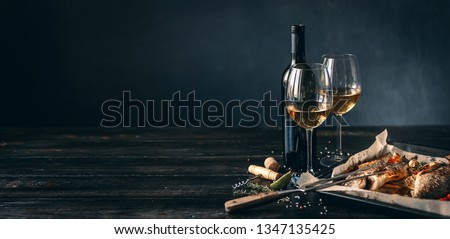 dinner concept for two. two glasses of white wine, baked fish.