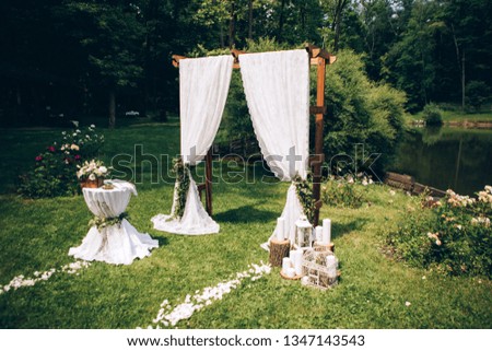 Outgoing wedding ceremony. Decor Studio. white wooden chairs on a green lawn. Wedding festal arch. White armchairs for guests