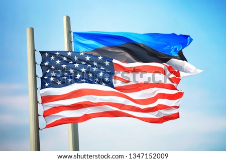 Flags of the USA and Estonia against the background of the blue sky
