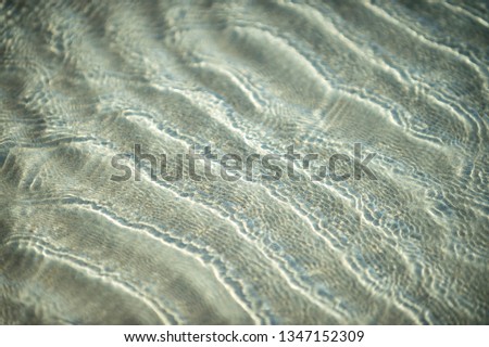 Natural background of clear shallow water rippling over sand in an abstract full frame close-up