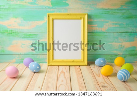 Photo frame or artwork display mock up on wooden table with easter eggs.