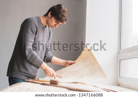 portrait of engineer designer in workshop with paper plans or schemes