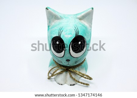Adorable wooden figure of a cat with big eyes.  Statue is isolated on white background and has light green colors.