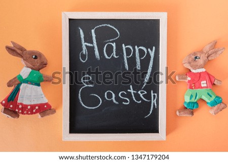 Easter picture with bunnies and a sign with an inscription on an orange background. Decorative concept