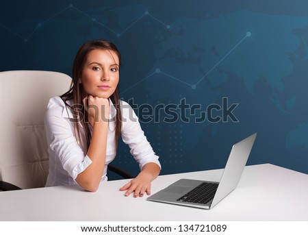 Pretty young woman sitting at desk and typing on laptop