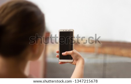 Cropped shot view of woman's hands holding smart phone with blank copy space screen for your text message or information content. Female reading text message on cell telephone during in urban setting.