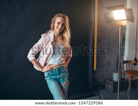 cheerful smiling girl in fashion clothe s standing with hands on the hips and looking at the camera. close up photo