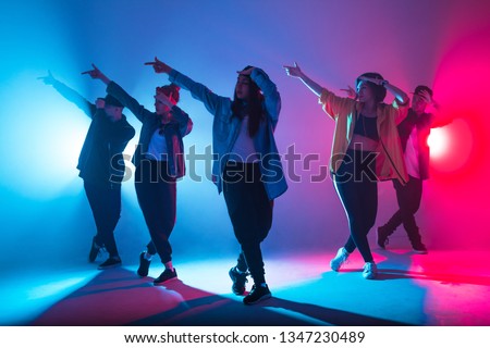 Young modern dancing group of six adult young people practice dancing on colorful background