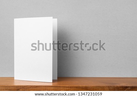Design concept - front view of greeting card on bookshelf and grey wall for mockup, not 3D render Royalty-Free Stock Photo #1347231059