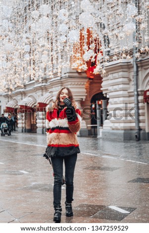 Young and adorable russian girl posing in front of Gum famous shop in Moscow on the Red Square through winter holiday