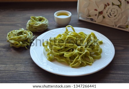 Colored fresh homemade pasta tagliatelle green spinach, old wooden table. Top view