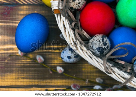 wicker basket with easter eggs and willow branches on a wooden table