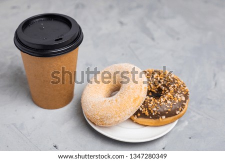 Colorful donuts and brown paper cup on Gray concrete background, close up, top view. Bakery concept, fresh pastries, delicious breakfast, fast food