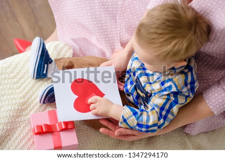 Happy family moment! Baby boy gives mother card and congratulates on holiday. Mother's day. Valentine's day