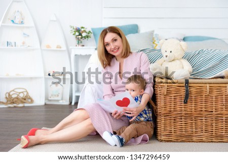 Happy family moment! Baby boy gives mother card and congratulates on holiday. Mother's day. Valentine's day.