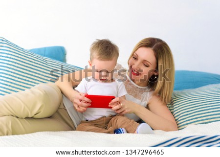 Baby boy sitting with mom and playing on smartphone