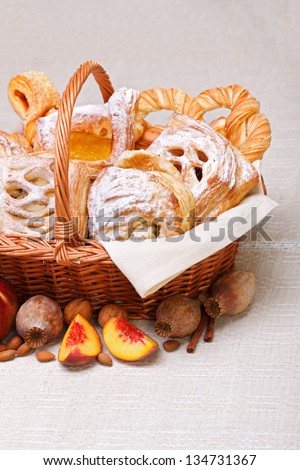 Lots of sweet cakes in basket, fruit and poppy decoration around