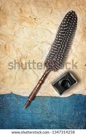 Mockup of empty old vintage yellowed paper sheet with luxury quill pen and bottle of black ink on blue concrete background
