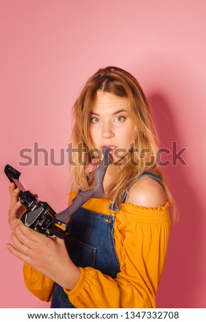 Funny retro styled fashionable woman portrait with vintage film camera on pink background. Fashion back to 80s - 90s new trend concept
