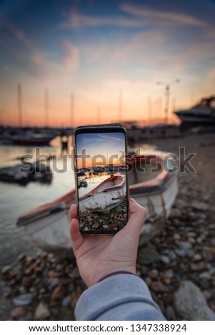 Phone holding and taking picture of a fishing boat