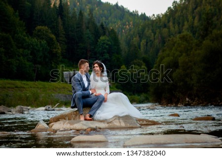 Happy newlyweds standing and smiling on the river . Honeymooners, photo for Valentine's Day.