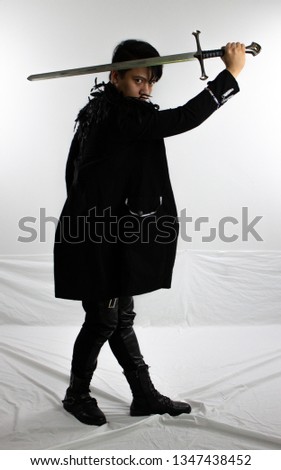 Young man in black coat wielding sword