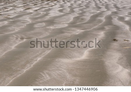 Background and texture photo of brown color sand with pile of sand from small crab and ripple shape from the sea on the beach.