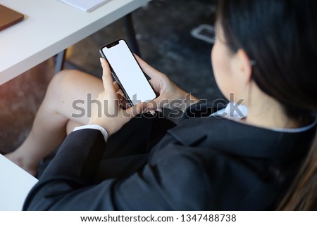 Cropped shot view of women hands holding smart phone with blank copy space screen for your text message or information content, female reading text message on cell telephone during in urban setting. 