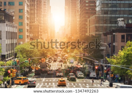 View of Second Avenue in New York city is crowded with cars and people in Manhattan with the bright light of sunset in the background