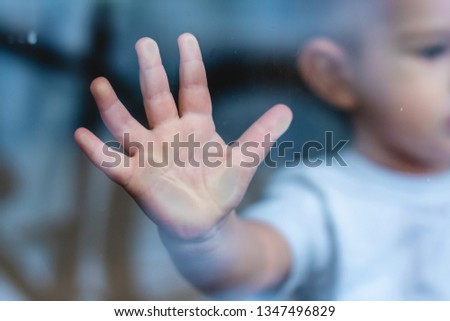 The child's small hand is pressed against the window glass with reflection. The concept of loneliness of children and waiting for kindness. Orphanage and orphans Royalty-Free Stock Photo #1347496829