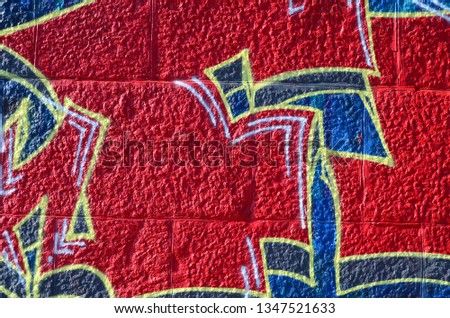 Fragment of graffiti drawings. The old wall decorated with paint stains in the style of street art culture. Colored background texture in warm tones