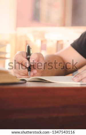 Take notes in the book,Take notes in the book The right hand of a man writes a note on the notebook that is placed on a wooden table.