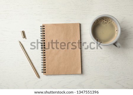 Notebook and cup of coffee on wooden background, top view