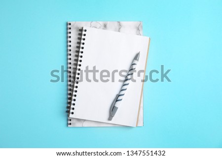 Notebooks and pen on color background, top view