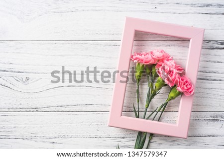 Design concept - top view of bunch of beautiful carnation with photo frame on white vintage wooden background for mothers day, wedding and valentines day with copy space for mock up