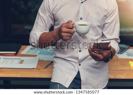 Business and finance concept of office working, Businessman using smartphone and holding coffee cup in office