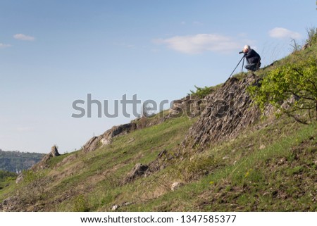 The photographer is doing a landscape shooting. He is located on the slope.