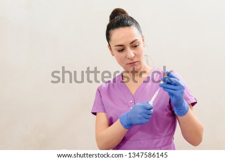 Young professional cosmetologist getting liquid into the syringe from bottle