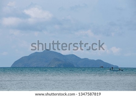 Mountain with Local Fisherman Boats on the right side floating over the sea with bright sky in background in the afternoon at Koh Mak Island in Trat, Thailand.