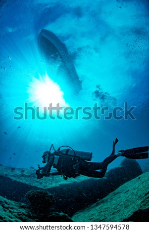boat from underwater with sun rays and scuba diver