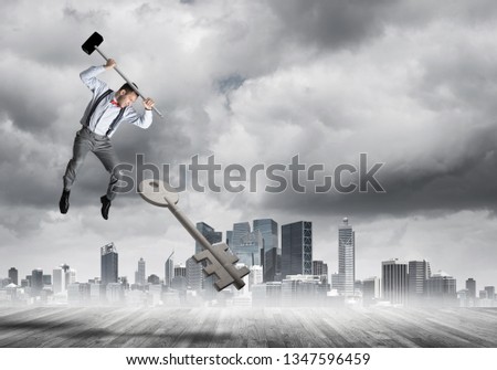 Determined businessman against cityscape breaking with hammer stone key figure